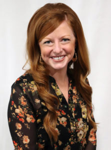 Ashley Zwak - Woman smiling with floral shirt and red hair