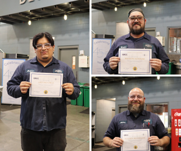 Three workers smiling with their certificates